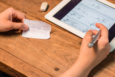 People writting statistic fomula from tablet to a piece of paper