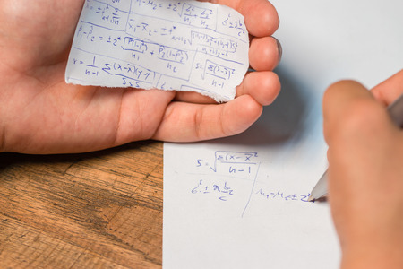 People cheating on test by wrote answer on piece of paperの写真素材