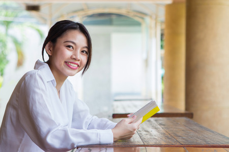 Asian woman reading book on the table with blurry backgroundの写真素材