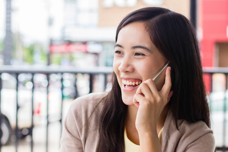 Asian woman calling on her phone with bluryy backgroundの写真素材
