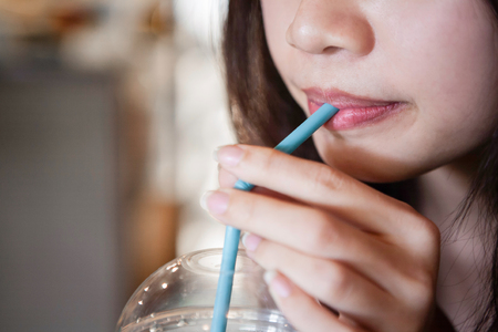 Close up of mouth drinking from straw with blurry backgroundの写真素材