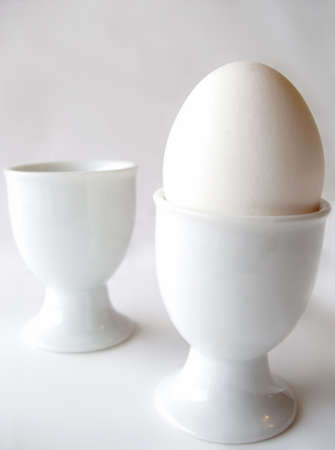 one white egg - two white egg cupsの写真素材
