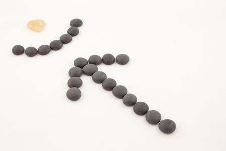 arrow and goal from black and beige stones on a white backgroundの写真素材