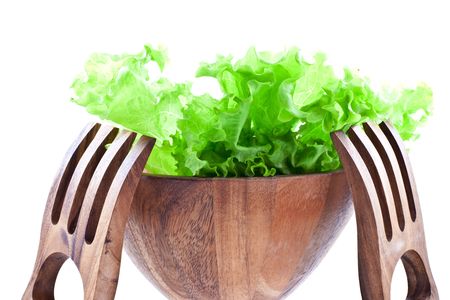 green lettuce leaves in a wood salad bowl with two big wood forks on a white backgroundの写真素材