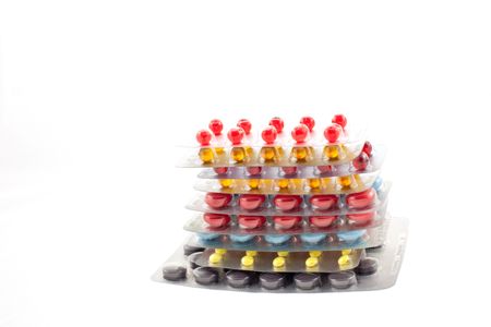 a number of multicolor pill blisters one upon the other on a white background