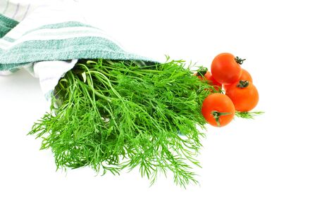 dill bunch in green kitchen towel and tomatoes on white backgroundの写真素材