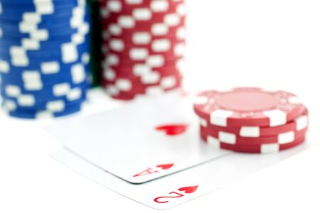 Three color poker chip stacks and cards on white background