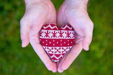 man hands with red knitted heart. valentine's symbolの写真素材