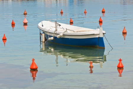 Boat on water and many red buoyes around it. の写真素材