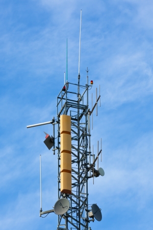 A radio communications tower with dishes against a blue skyの写真素材