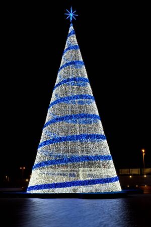 Pine christmas tree figure with blue and white lights against a black backgroundの写真素材