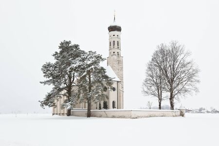Beautiful Alpine bavarian Church after morning snowfall in mountain villageの写真素材