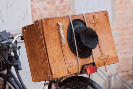 Shabby black hat and brown suitcase on the old bike. Horizontal imageの写真素材