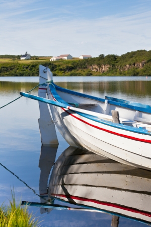 Floating Wooden Boat with Paddles and Its Reflection in a Waterの写真素材