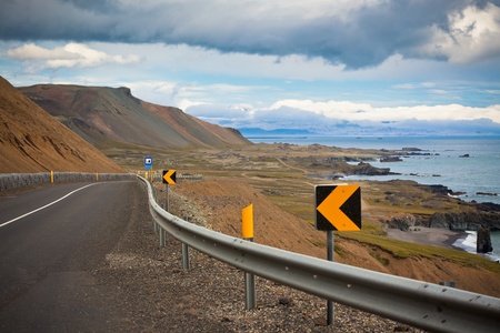 Highway through dry gravel mountains at sea coastline of East Iceland.の写真素材