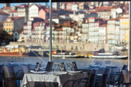 Cozy Restaurant tables ready for service with Porto cityscape view. Defocused blur shot