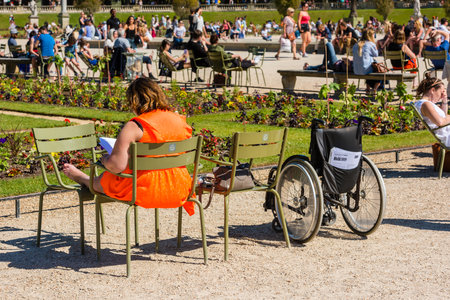 FRANCE, PARIS - JUNE 06: Woman sitting on a chair in the park and reading a book on June 06, 2015.のeditorial素材