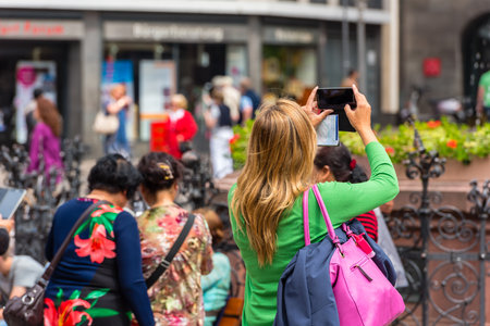 GERMANY, FRANKFURT - MAY 24: Back side of young woman taking a photo with her phone in Frankfurt on May 24, 2015のeditorial素材