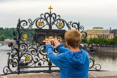 THE CZECH REPUBLIC, PRAGUE - MAY 19: Tourist touching the sculpture of Saint Jan Nepomuk on the...
