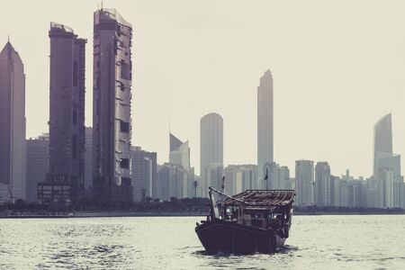 Abu Dhabi buildings skyline with old fishing boat on the frontの写真素材