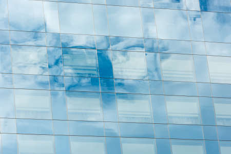 blue sky and clouds reflected in windows of modern office buildingの写真素材