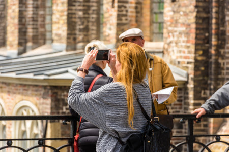 BELGIUM, BRUGES - MAY 22: Woman is taking pictures on the street of Bruges on May 22, 2015のeditorial素材