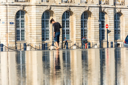 FRANCE, BORDEAUX - SEPTEMBER 20: People having fun in a mirror fountain in front of Place de la Bourse in Bordeaux, France on September 20, 2015のeditorial素材