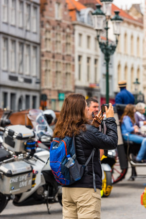 BELGIUM, BRUGES - MAY 22: Woman is taking pictures on the street of Bruges on May 22, 2015のeditorial素材