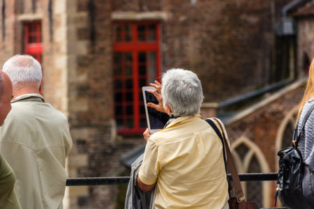 BELGIUM, BRUGES - MAY 22: Woman is taking pictures on the street of Bruges on May 22, 2015のeditorial素材