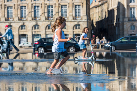 FRANCE, BORDEAUX - SEPTEMBER 20: People having fun in a mirror fountain in front of Place de la Bourse in Bordeaux, France on September 20, 2015のeditorial素材
