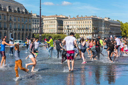 FRANCE, BORDEAUX - SEPTEMBER 20: People having fun in a mirror fountain in front of Place de la Bourse in Bordeaux, France on September 20, 2015のeditorial素材
