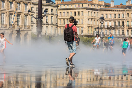 FRANCE, BORDEAUX - SEPTEMBER 20: People having fun in a mirror fountain in front of Place de la Bourse in Bordeaux, France on September 20, 2015のeditorial素材