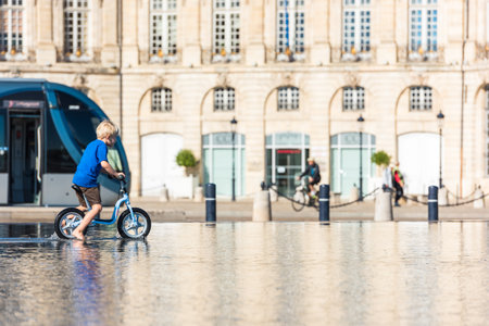 FRANCE, BORDEAUX - SEPTEMBER 20: Children having fun in a mirror fountain in front of Place de la Bourse in Bordeaux, France on September 20, 2015のeditorial素材