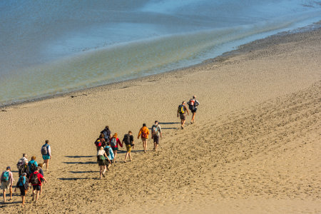 FRANCE, MONT SAINT MICHEL - SEPTEMBER 26: View from walls of Mont Saint Michel on the bay during the low tide with groups of tourists walking. France on September 26, 2015のeditorial素材