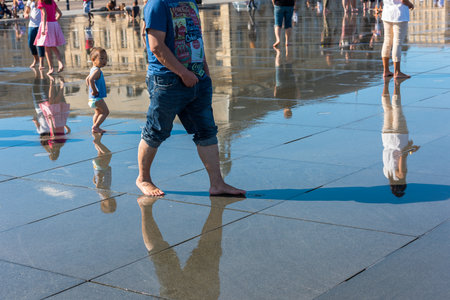 FRANCE, BORDEAUX - SEPTEMBER 20: People having fun in a mirror fountain in front of Place de la Bourse in Bordeaux, France on September 20, 2015のeditorial素材