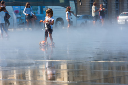 FRANCE, BORDEAUX - SEPTEMBER 20: People having fun in a mirror fountain in front of Place de la Bourse in Bordeaux, France on September 20, 2015のeditorial素材
