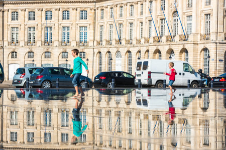 FRANCE, BORDEAUX - SEPTEMBER 20: People having fun in a mirror fountain in front of Place de la Bourse in Bordeaux, France on September 20, 2015のeditorial素材