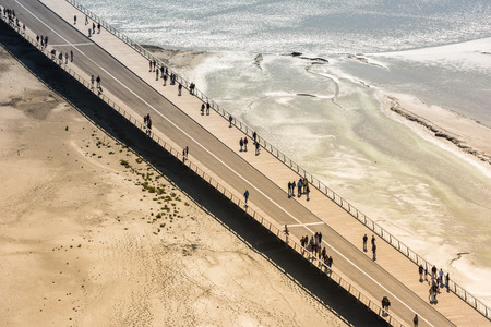 View from walls of Mont Saint Michel on the bay during the low tide. Groups of tourists walking. Franceの写真素材