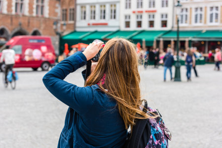 BELGIUM, BRUGES - MAY 22: Woman is taking pictures on the street of Bruges on May 22, 2015のeditorial素材