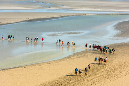 FRANCE, MONT SAINT MICHEL - SEPTEMBER 26: View from walls of Mont Saint Michel on the bay during the low tide with groups of tourists walking. France on September 26, 2015のeditorial素材