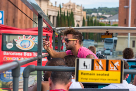 SPAIN, BARCELONA - SEPTEMBER 13: Tourists enjoy sightseeing tour on a hop-on-hop-off city bus in Barcelona on September 13, 2015のeditorial素材