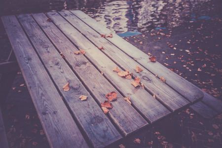 Fallen autumn leaves on a wooden table in the town. Filtered shot