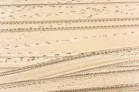 Traces of car tires on the sand as a backgroundの写真素材
