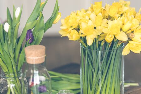 Yellow narcissuses bouquet in a glass vase. Indoors natural light shot with small depth of fieldの写真素材