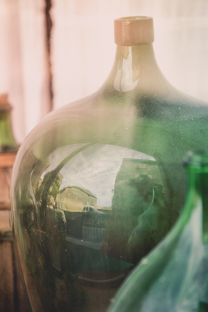 Old empty wine bottles behind the glass with street reflectionの写真素材
