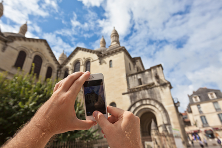 Tourist hands holding smart phone taking photo of Perigueux, Franceの写真素材
