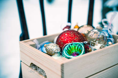Christmas decoration balls in a wooden box outdoors on winter snow background