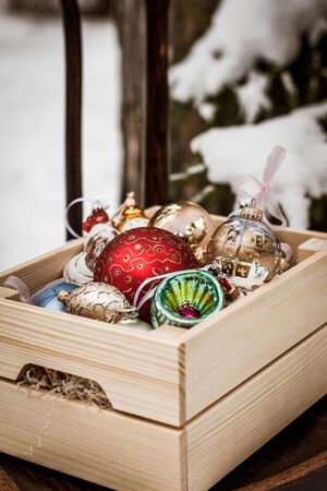 Christmas decoration balls in a wooden box outdoors on winter snow backgroundの写真素材