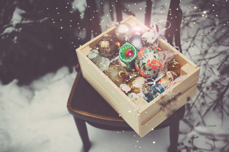 Christmas decoration balls in a wooden box outdoors on winter snow background
