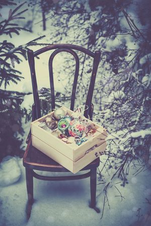 Christmas decoration balls in a wooden box outdoors on winter snow backgroundの写真素材